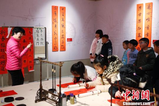 孩子在老师的指点下书写春联。 殷立勤 摄