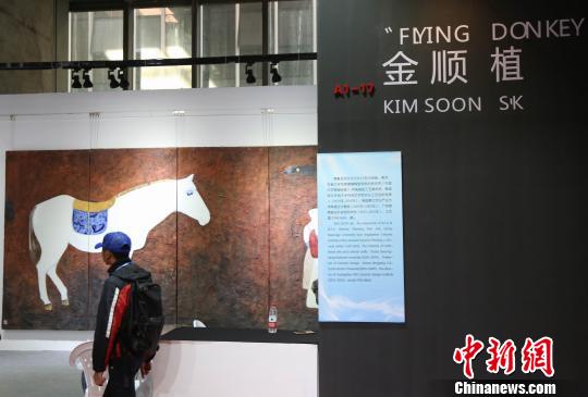 韩国参展企业展位前，一位游客正在欣赏作品。　姜涛 摄